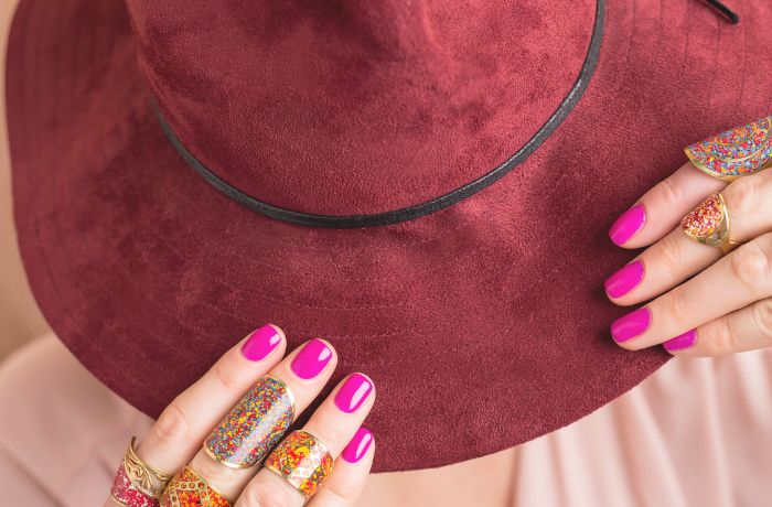 Mujer tocando su sombrero con sus uñas cortas maquilladas.